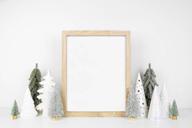 Noel, ahşap çerçeve ve yeşil ve beyaz Noel ağacı dekoru ile süslenir. Beyaz bir duvara dayalı beyaz bir raftaki portre çerçevesi. Boşluğu kopyala.