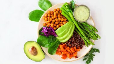 Kuşkonmaz, kinoa, tatlı patates, nohut ve avokado ile sağlıklı vejetaryen yemek kasesi. Yavaş zum hareketi. Beyaz mermer bir arkaplan üzerinden genel görünüm.