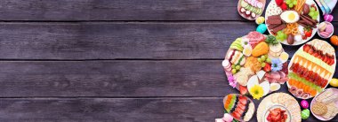 İlkbahar ya da Paskalya otlatma kurulu temalı tema kenarı koyu ahşap bir afişe karşı. Manzaranın üstünde. Çeşitli tatlı ve peynir, et ve meyve aperatifleri. Boşluğu kopyala.