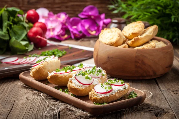 Torradas com rabanete, cebolinha e queijo cottage em uma mesa de madeira . — Fotografia de Stock