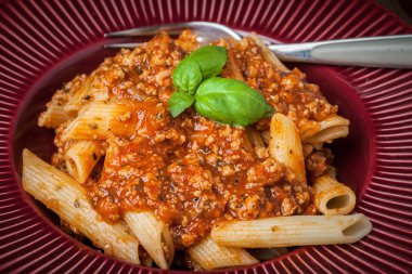 Penne bolognese beyaz plaka üzerinde.