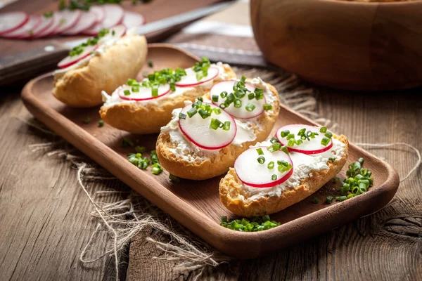 Torradas com rabanete, cebolinha e queijo cottage em uma mesa de madeira . — Fotografia de Stock