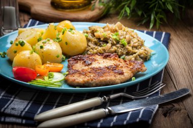 Kızarmış domuz eti, fırında patates ve kızarmış genç lahana.