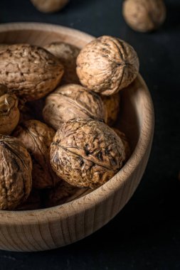 Koyu arkaplanda ahşap bir kasede ceviz..