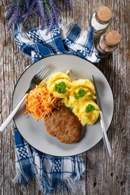 Patates püresi ve havuç salatasıyla servis edilen ev yapımı kıymalı pirzola..