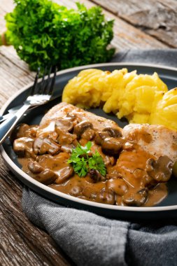 Mantar soslu ızgara tavuk göğsü, patates püresi ve salatalık turşusu ile servis edilir..