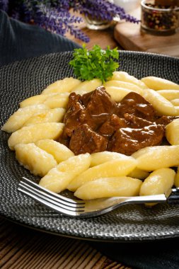 Soslu sığır eti yahnisi, patates köftesiyle servis edilir..