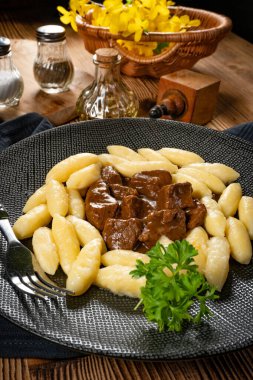 Soslu sığır eti yahnisi, patates köftesiyle servis edilir..