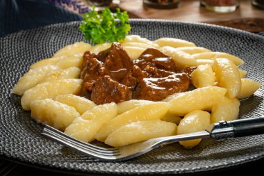 Soslu sığır eti yahnisi, patates köftesiyle servis edilir..