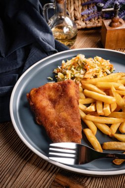 Kızarmış balık fileto, yanında patates kızartması ve salata..