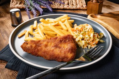 Kızarmış balık fileto, yanında patates kızartması ve salata..