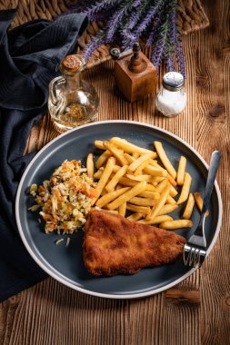 Kızarmış balık fileto, yanında patates kızartması ve salata..