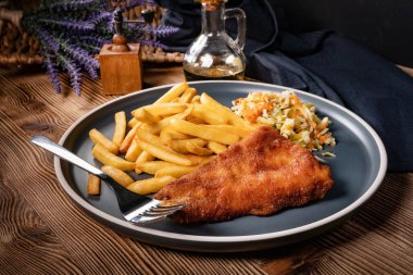 Kızarmış balık fileto, yanında patates kızartması ve salata..