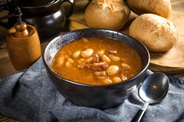 Domates soslu fasulye, pastırma ve siyah kasede sosis. Seçici odak.