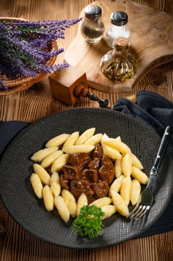 Soslu sığır eti yahnisi, patates köftesiyle servis edilir..