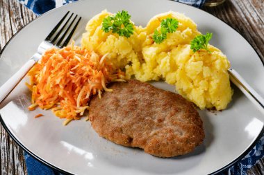 Patates püresi ve havuç salatasıyla servis edilen ev yapımı kıymalı pirzola..