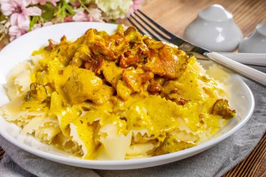 Kremalı kızarmış tavuklu makarna ve ahşap masada chanterelle sosu..