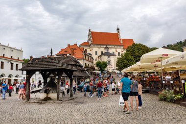 KAZIMIERZ DOLNY, POLAND 23 AĞUSTOS 2020: eski kasaba meydanında turistler. Aziz John Kilisesi ve St. Bartholomew Kilisesi..