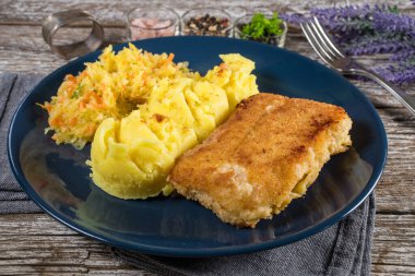 Haşlanmış patates ve sebze salatasıyla servis edilen kızarmış morina filetosu..