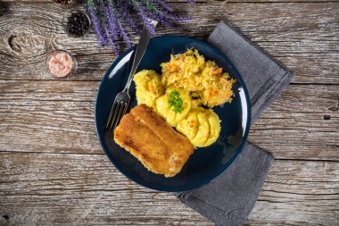 Haşlanmış patates ve sebze salatasıyla servis edilen kızarmış morina filetosu..