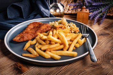 Kızarmış balık fileto, yanında patates kızartması ve salata..