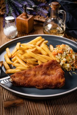 Kızarmış balık fileto, yanında patates kızartması ve salata..