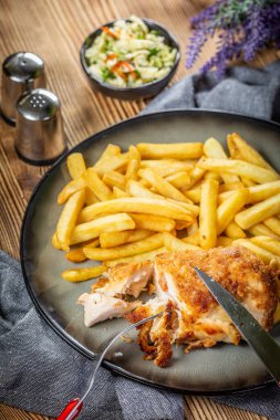 Pastırma ve peynirle doldurulmuş kızarmış tavuk göğsü patates kızartması ve salata ile servis edilir. Küçük alan derinliği.