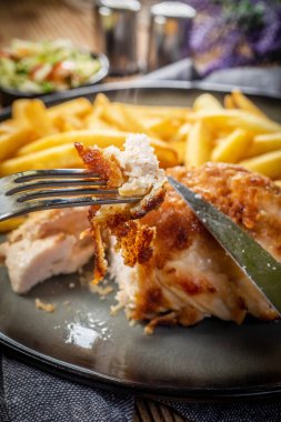 Pastırma ve peynirle doldurulmuş kızarmış tavuk göğsü patates kızartması ve salata ile servis edilir. Küçük alan derinliği.