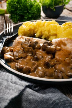 Mantar soslu ızgara tavuk göğsü, patates püresi ve salatalık turşusu ile servis edilir..