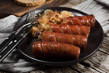 Siyah tabakta soğanlı kızarmış sosis..