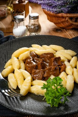 Soslu sığır eti yahnisi, patates köftesiyle servis edilir..