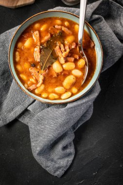 Domates soslu fasulye, pastırma ve siyah kasede sosis. Seçici odak.