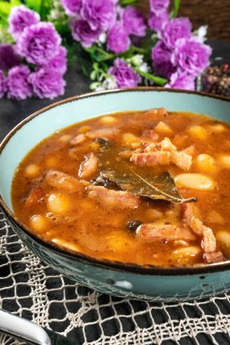 Domates soslu fasulye, pastırma ve siyah kasede sosis. Seçici odak.