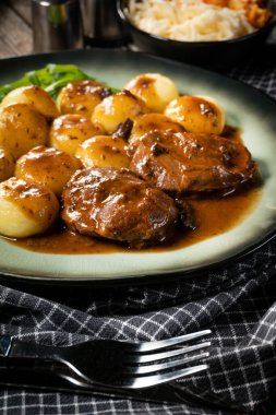 Geleneksel Alman haşlanmış domuz yanakları kahverengi soslu ve mantarlı Silezya köftesi ile servis ediliyor..