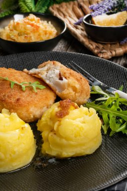 Haşlanmış patates ve sebze salatasıyla servis edilen kızarmış morina filetosu..