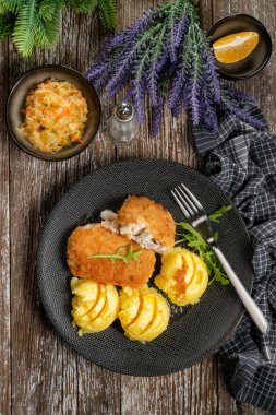 Haşlanmış patates ve sebze salatasıyla servis edilen kızarmış morina filetosu..