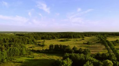 Batan güneşin ışığında çayırlar ve ormanlar.