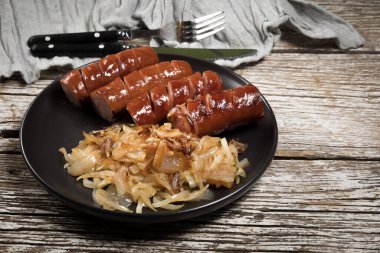 Siyah tabakta soğanlı kızarmış sosis..