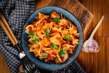 Domates soslu erişteli tavuk parçaları. Sığ alan derinliği.