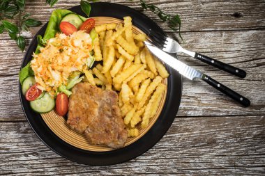 Geleneksel Polonya yemeği: kızarmış domuz pirzolası, patates kızartması ve salata ile servis edilir.. 