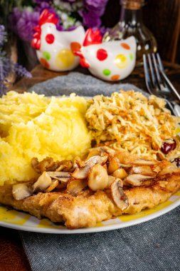 Patates püresi ve salatayla servis edilen geleneksel mantarlı domuz pirzolası..