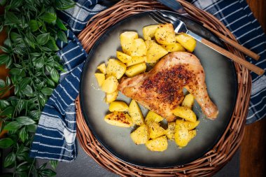 Akşam yemeğinde kızarmış patatesle servis edilen kahverengi derili iştah açıcı tavuk budu..