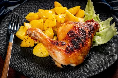 Appetizing baked chicken leg quarter with browned skin served with crispy fries for dinner.