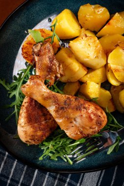 Fırında tavuk budu ve patates. Yüzeyin derinliği. Koyu ışık.