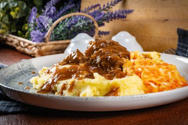 Patates püresi ve salatayla servis edilen soslu domuz budu.