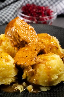 Patates püresi ve rendelenmiş pancar ile servis edilen soslu domuz budu..