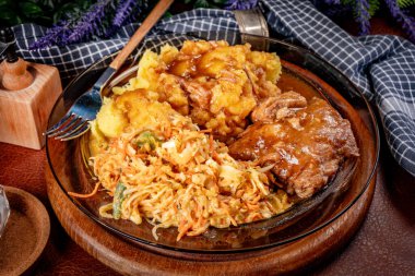 Patates püresi ve salatayla servis edilen acılı soslu domuz pirzolası. Sığ alan derinliği.