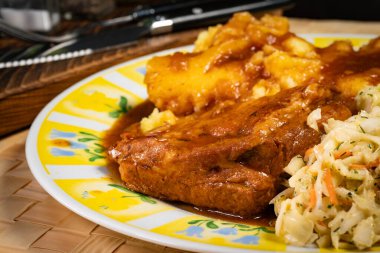 Patates püresi ve salatayla servis edilen acılı soslu domuz pirzolası. Sığ alan derinliği.