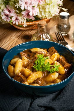 Soslu sığır eti yahnisi, patates köftesiyle servis edilir..