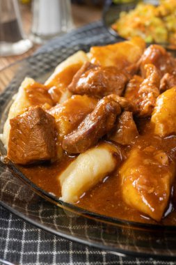 Soslu sığır eti yahnisi, patates köftesiyle servis edilir..